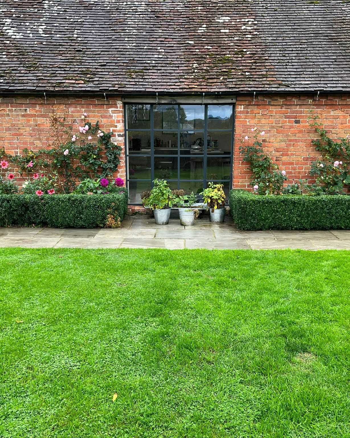 A bright green striped lawn in front of a brick garden building.