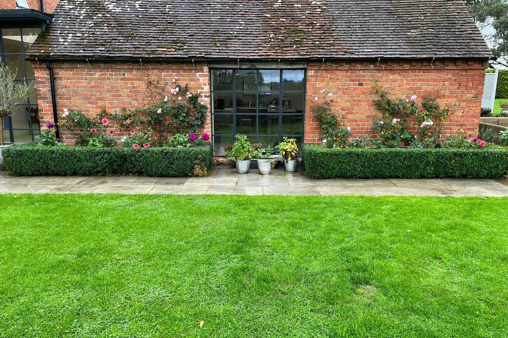A bright green striped lawn in front of a brick garden building.